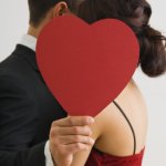 Hispanic couple hugging behind cut out heart